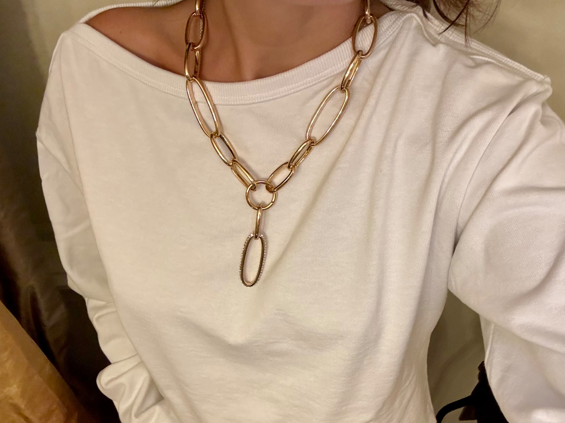 Collana dorata a maglie allungate indossata su una maglia bianca